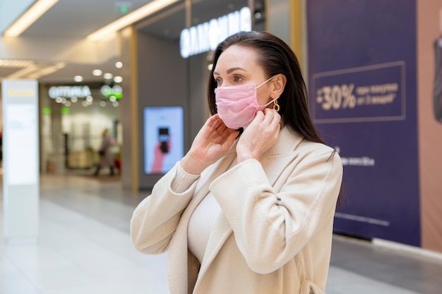 La mujer se pone una máscara protectora médica en un lugar público