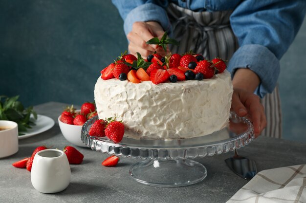 Mujer pone menta en pastel de crema de bayas