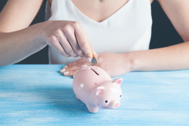 Una mujer pone una moneda en una alcancía.