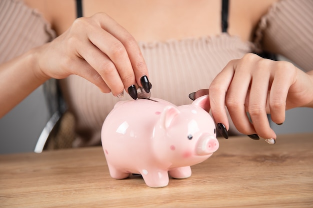 Una mujer pone una moneda en una alcancía.