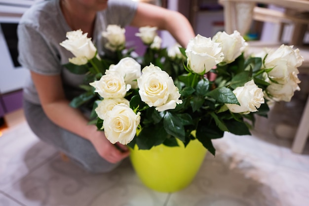 Mujer pone rosas blancas en una olla verde