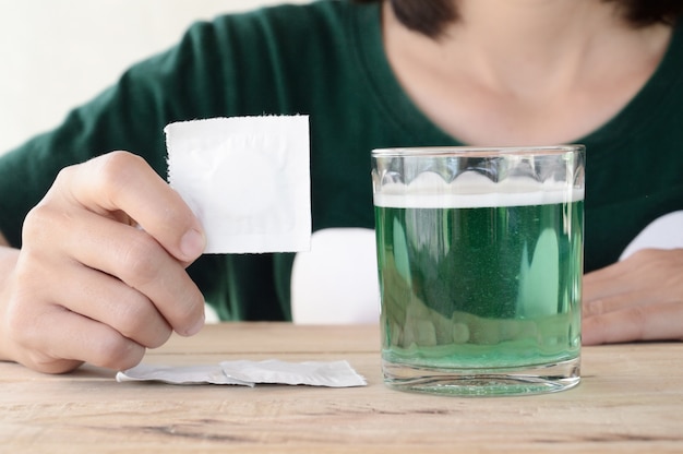 mujer pone tableta efervescente en vaso de agua en la mesa de madera