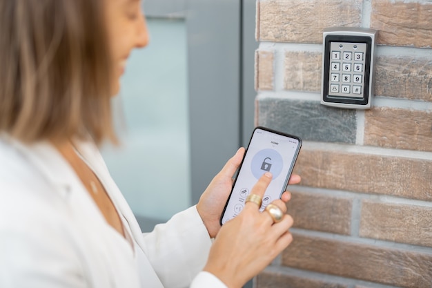 La mujer pone el teléfono inteligente al lector electrónico para acceder al apartamento u oficina. Celda con aplicación móvil segura en ejecución