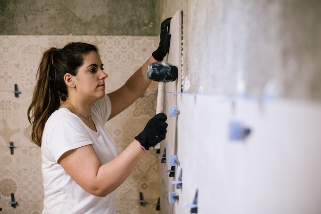 mujer poniendo azulejos en un baño nuevo