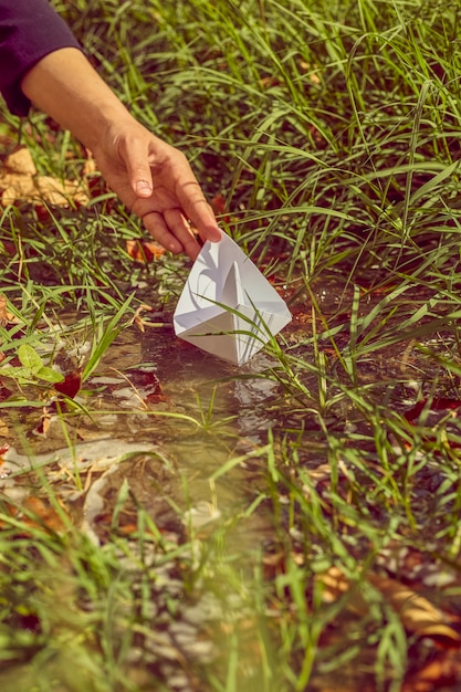 Mujer poniendo un barco de origami en el agua.