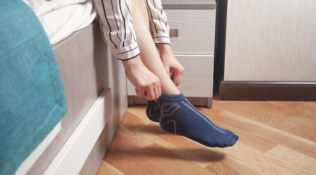 Foto mujer poniendo calcetines sentado en la cama.