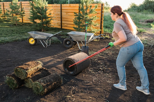 Mujer poniendo césped para el nuevo concepto de colocación de césped de césped de jardín