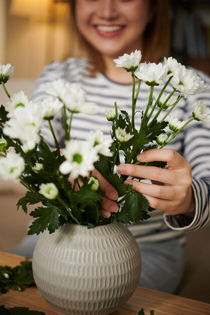 mujer, poniendo, crisantemo, flores, en, florero