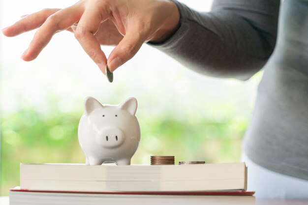 Mujer poniendo una moneda para ahorrar hucha, ahorrar dinero para el concepto de educación