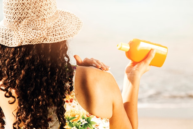 Foto mujer poniendo protector solar a orilla del mar