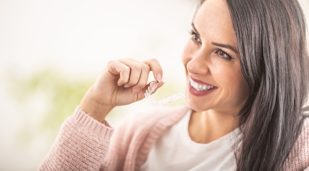 Mujer poniendo tirantes invisiline mientras sonríe.