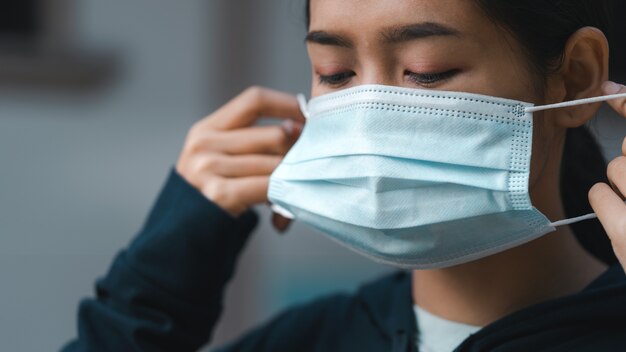 Mujer poniéndose una máscara médica para protegerse del virus.