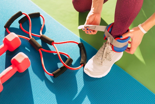 Mujer poniéndose pesas en los tobillos antes de comenzar un entrenamiento en un concepto de salud y fitness en el gimnasio