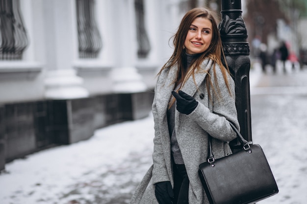 Mujer posando en abrigo gris fuera en invierno