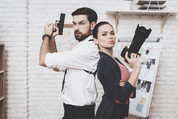 Foto la mujer está posando con la cámara, el hombre está posando con la pistola.