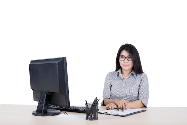 Mujer posando ante la cámara mientras trabaja en un escritorio