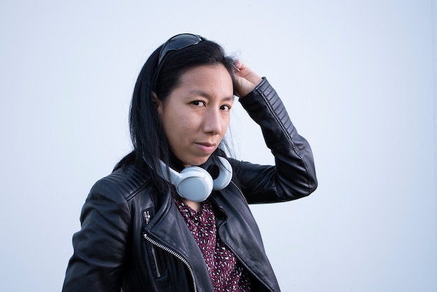 Mujer posando con chaqueta de cuero y auriculares de música