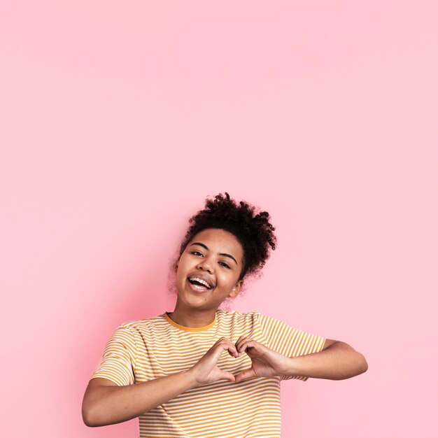 Foto mujer posando mientras hace la señal en forma de corazón