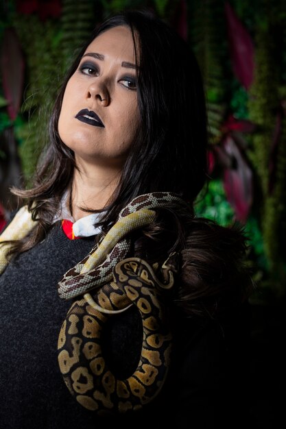 Foto mujer posando con serpiente en la pared oscura