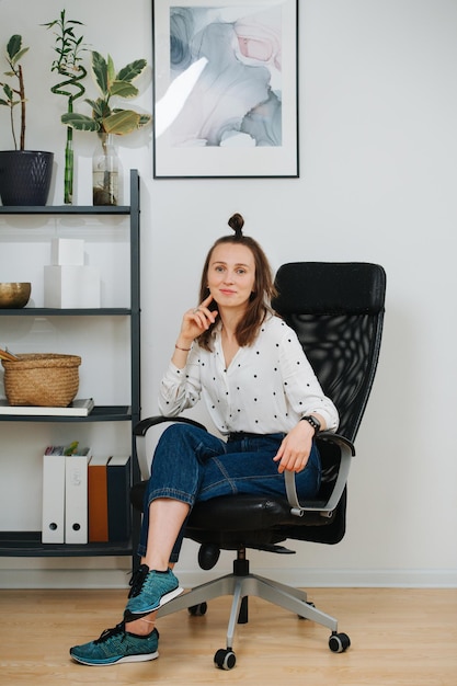 Mujer posando en una silla de escritorio en casa sonriendo a la cámara