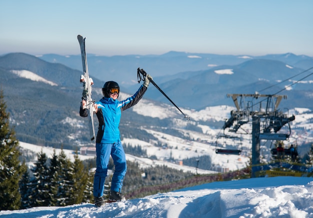 Mujer posando con sus esquís en la cima de las montañas