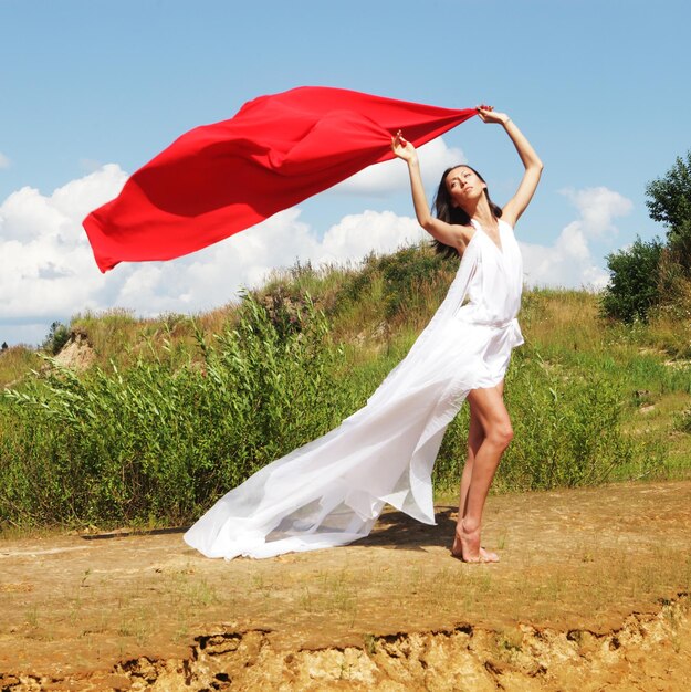 Mujer posando con tela roja al aire libre