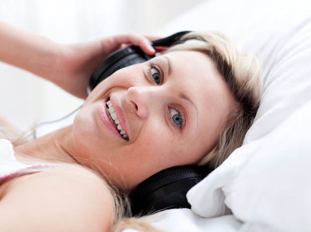 Mujer positiva con auriculares en acostado en una cama