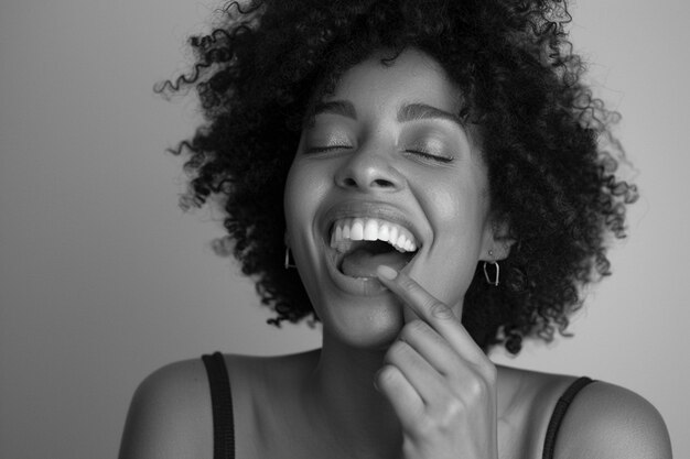 Mujer positiva con cabello rizado se ríe y se muerde el dedo