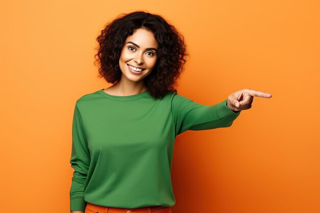 Foto mujer positiva y emocionada con camisa verde mirando hacia un espacio vacío aislado con fondo de color naranja