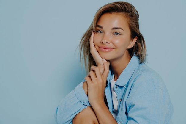 Mujer positiva expresando felicidad sobre fondo azul claro