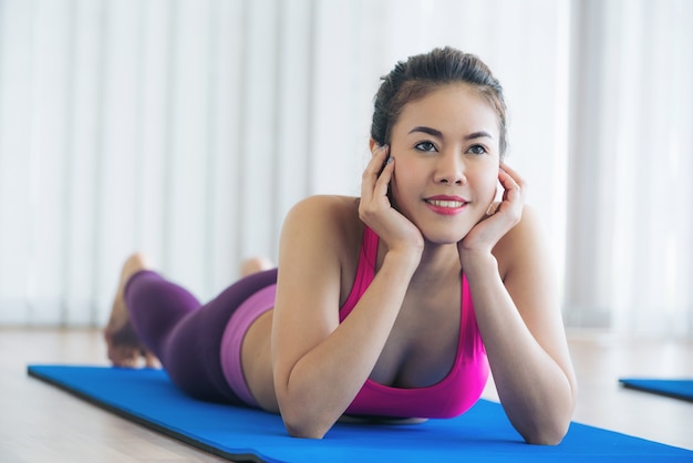 Mujer en la práctica de ropa deportiva entrenamiento de yoga que se extiende en el gimnasio en el interior.