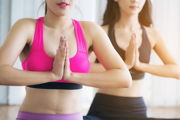 Mujer en la práctica de ropa deportiva entrenamiento de yoga que se extiende en el gimnasio en el interior.