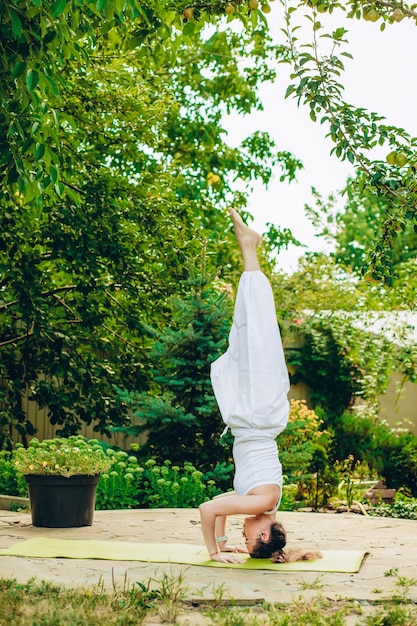 Foto mujer practica yoga en el jardín de verano salamba sirsasana ii tripod headstand