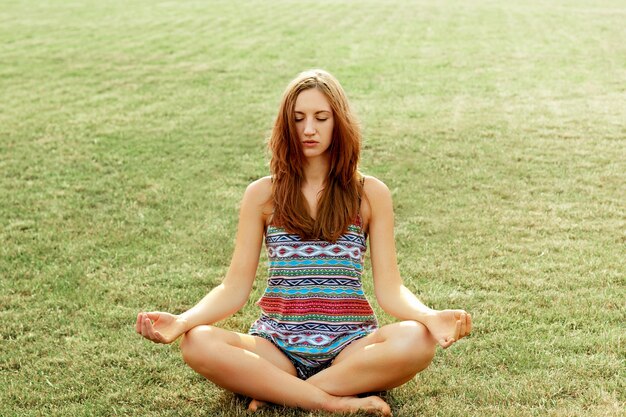 Mujer practica yoga y medita en posición de loto en la playa