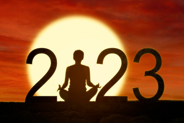 Mujer practica yoga mientras se sienta con números 2023