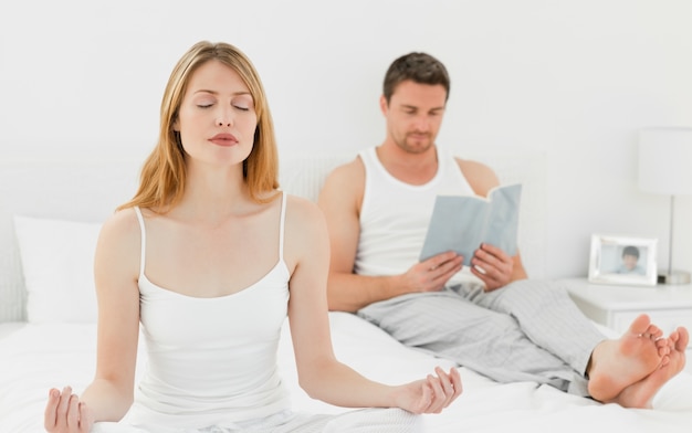 La mujer practica yoga mientras su marido está leyendo