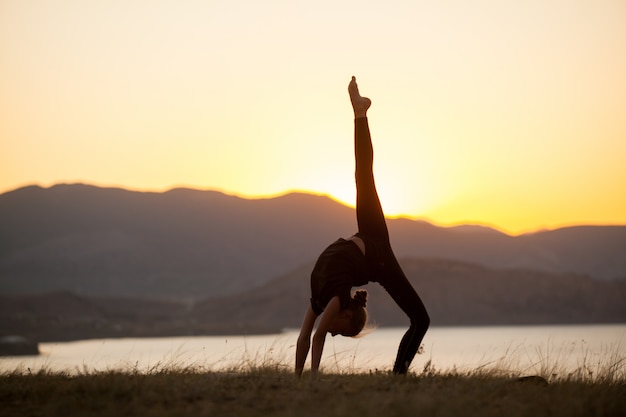 Mujer practica yoga en las montañas en el océano.