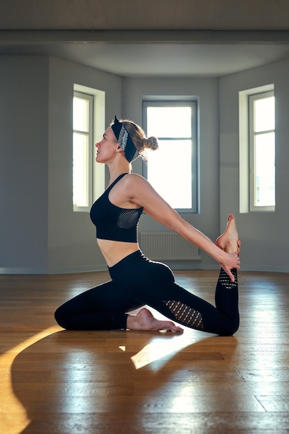 Una mujer practica yoga en una sala de fitness al amanecer