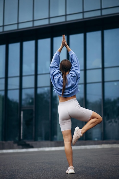 Mujer practicando árbol asana en la ciudad