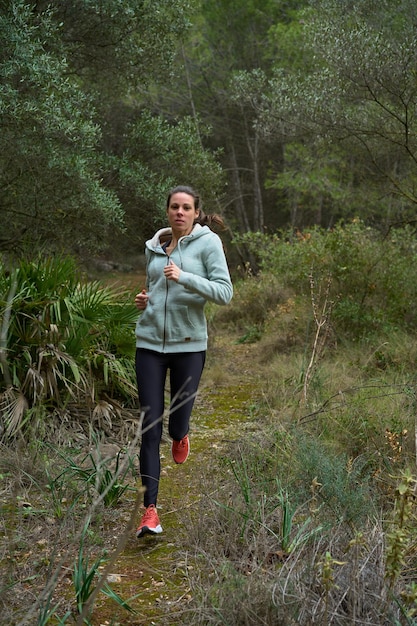 Mujer practicando deportes corriendo en una vista frontal de carretera de montaña