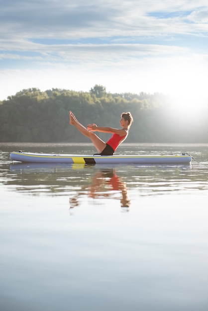 Mujer practicando yoga durante el amanecer en paddle board