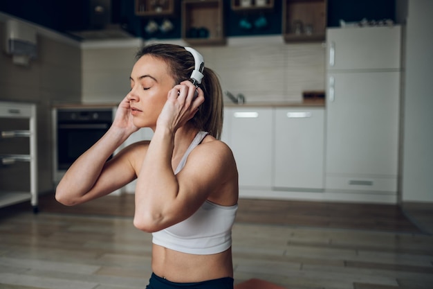 Mujer practicando yoga en casa y escuchando música con auriculares