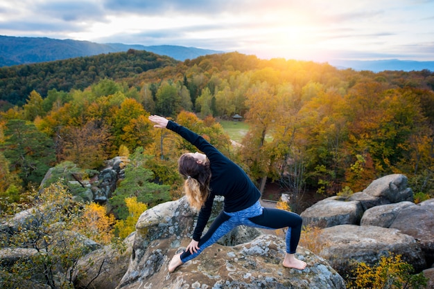 Mujer practicando yoga en la cima de la montaña en la noche