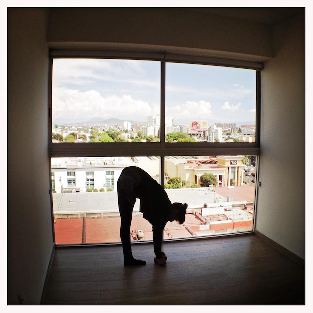 Foto mujer practicando yoga contra la ventana