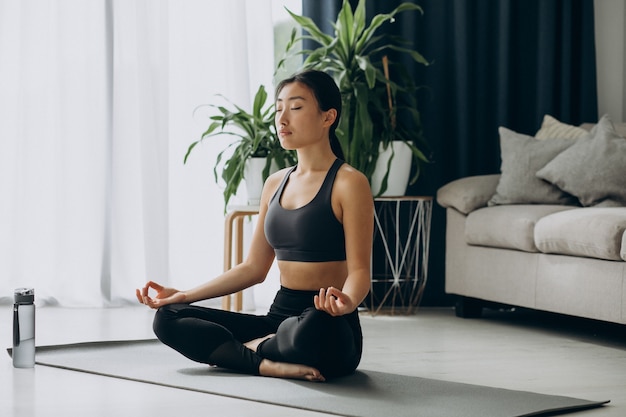 Mujer practicando yoga en estera en casa