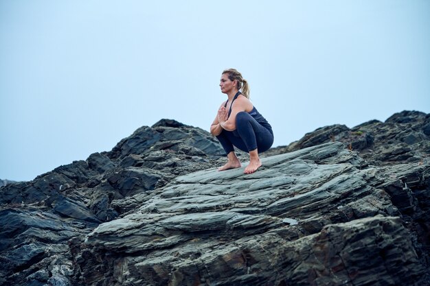 mujer practicando yoga frente al mar