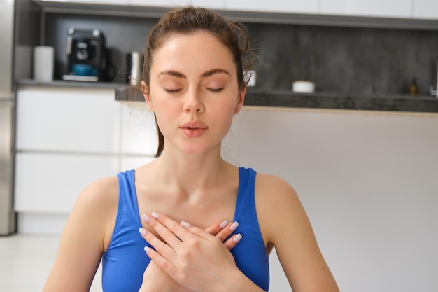 Mujer practicando yoga y meditación en casa sentada en postura de loto sobre una estera de yoga relajada con cerrado