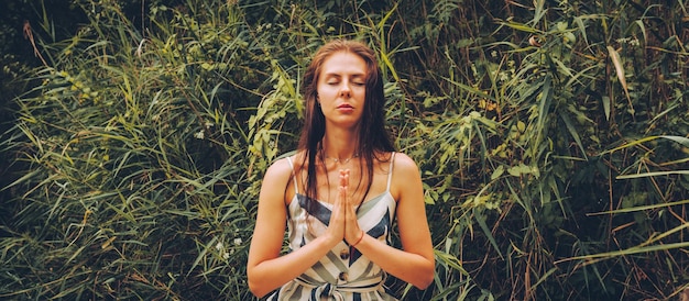 Foto mujer practicando yoga en el muelle junto al río mujer joven con vestido en postura de loto