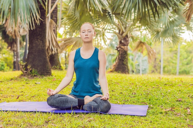 Mujer practicando yoga en un parque tropical.