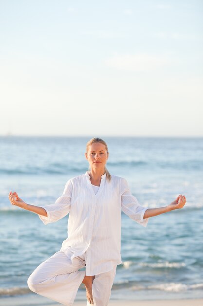 Mujer practicando yoga en la playa